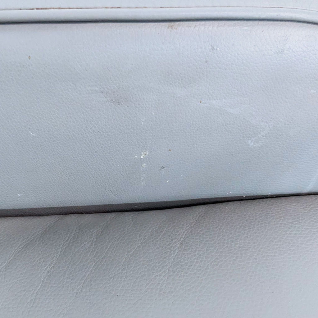Close-up of gray leather texture with visible marks and light wear.