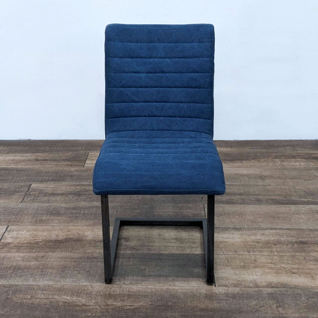 Modern dining chair with metal frame and blue upholstered seat, featuring channel tufting.