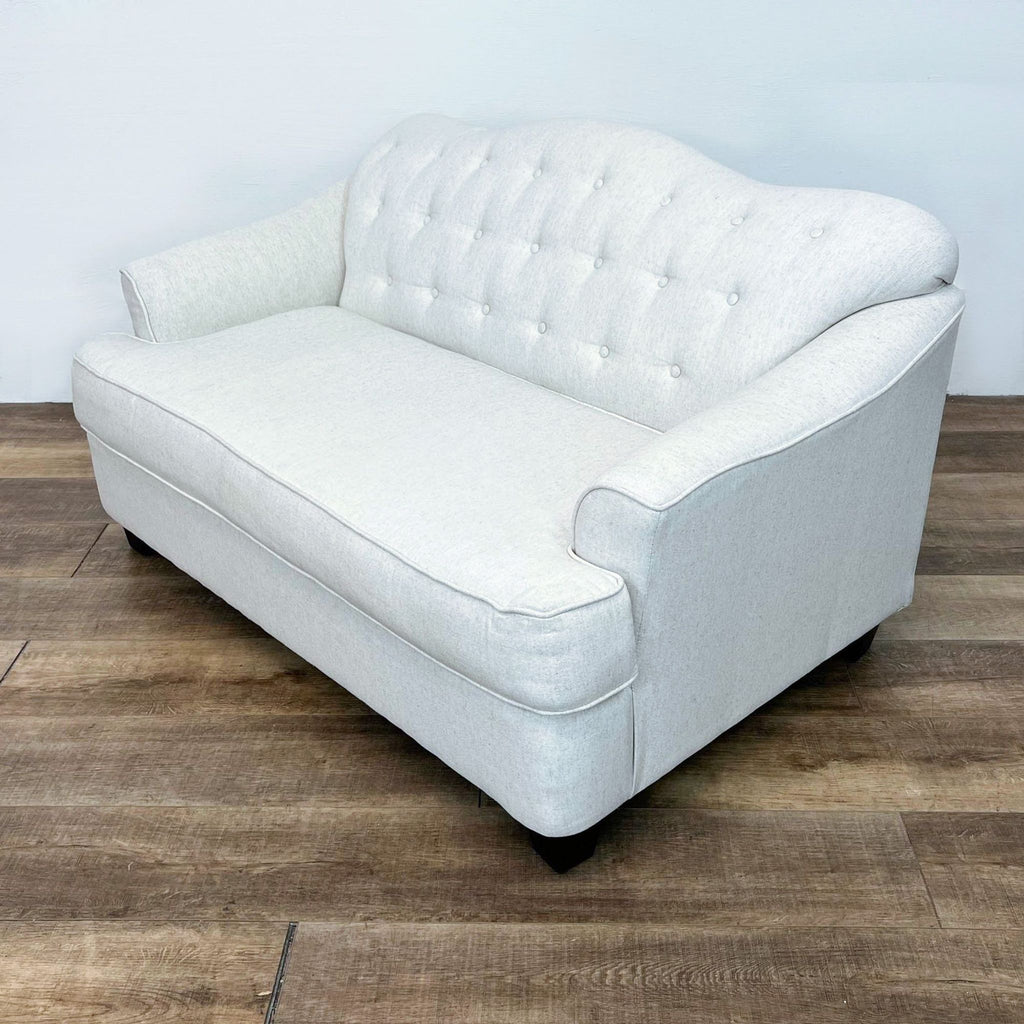 Angled view of a linen-look loveseat showcasing button tufting and a curved back.