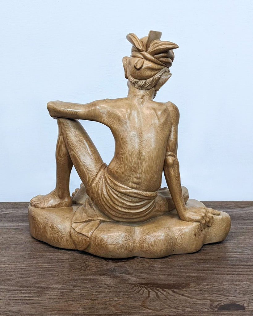 a statue of a man sitting on a wooden table 