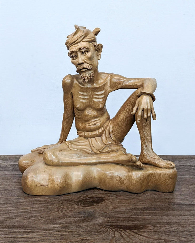 a statue of a man sitting on a wooden table 