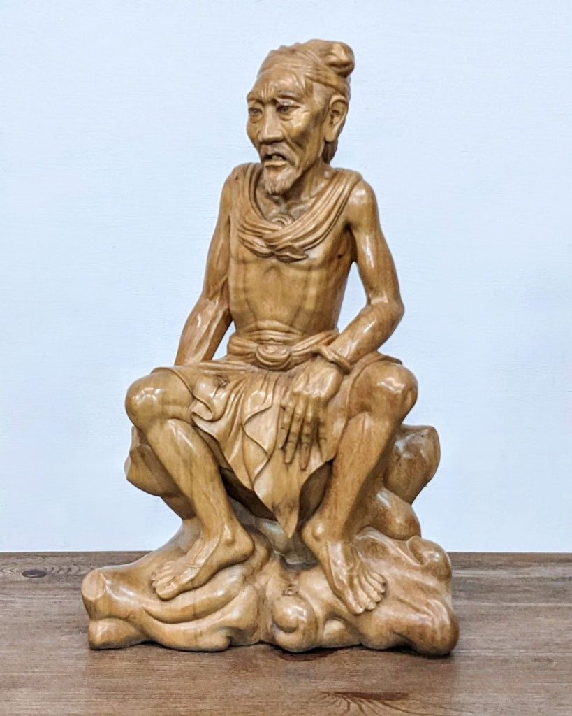 a statue of a man sitting on a wooden table 