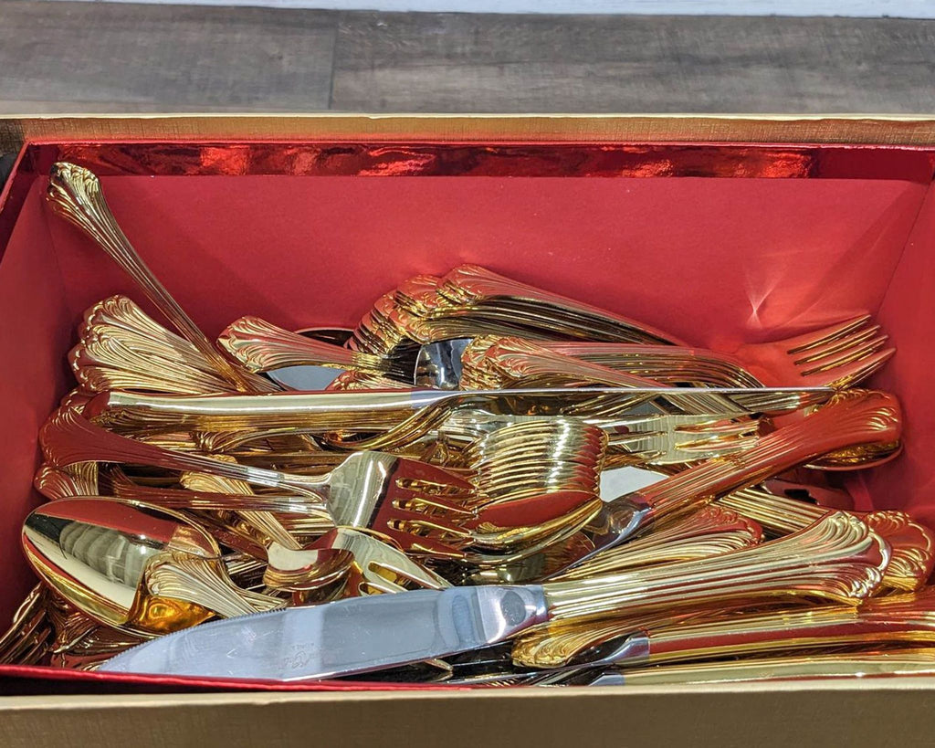 Gold flatware set with ornate design in an elegant gift box.