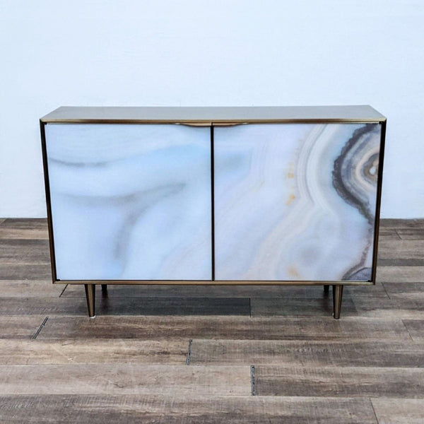 Caracole cabinet with agate printed acrylic doors, brushed gold finish, and conical feet.