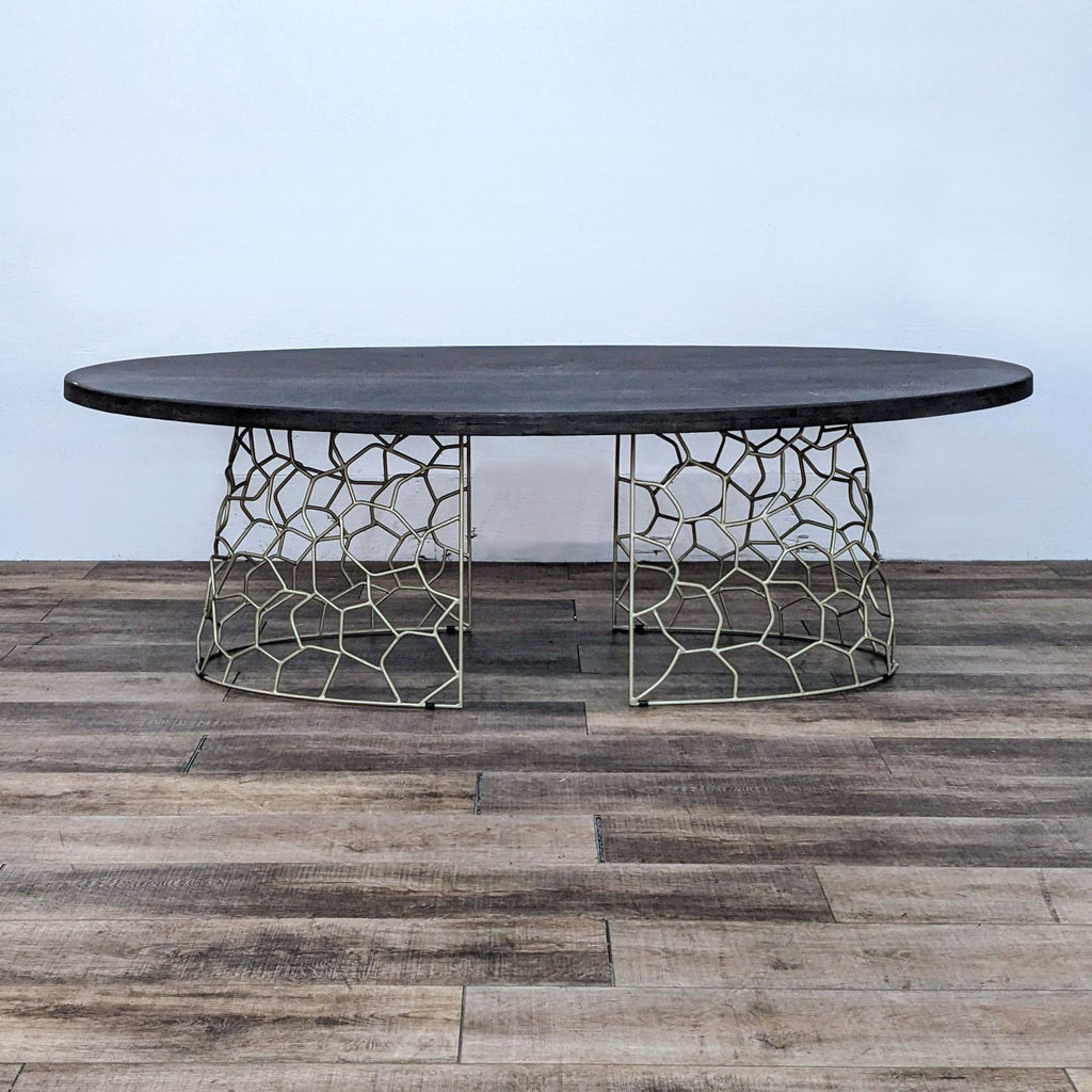 Contemporary oval dining table with a gold geometric base.
