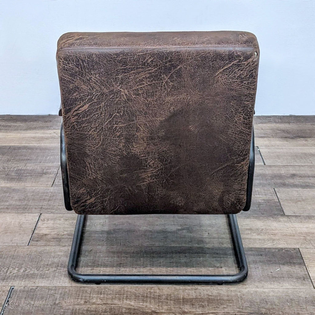 Rear view of the lounge chair with distressed brown leatherette fabric and robust frame.