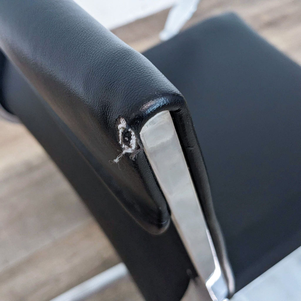 Close-up of a chair's upholstery showing a small tear on the armrest.
