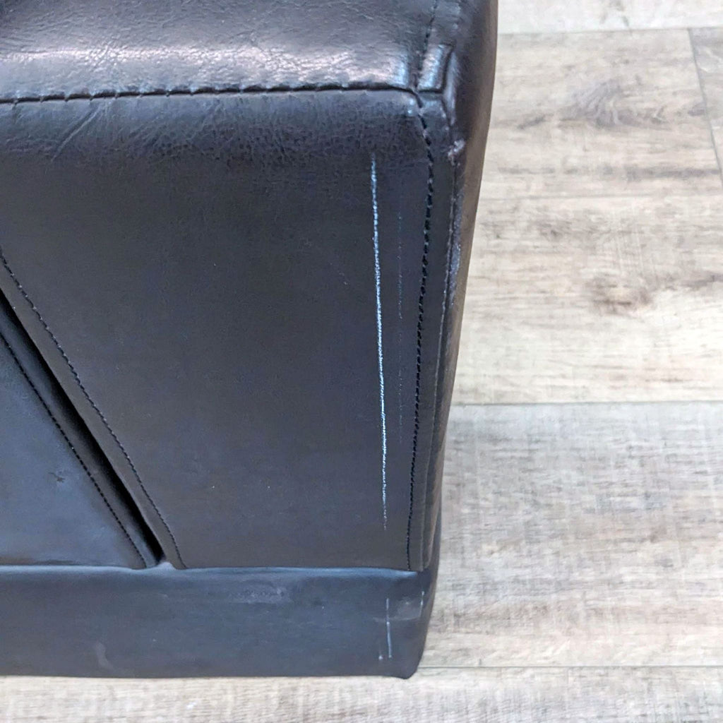 Close-up of Reperch lounge chair corner, highlighting faux leather texture and stitching.