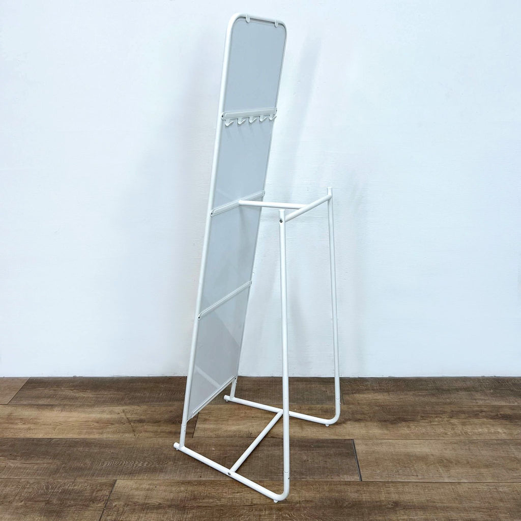 White-framed Ikea mirror with back hooks and a rod for hanging clothes.