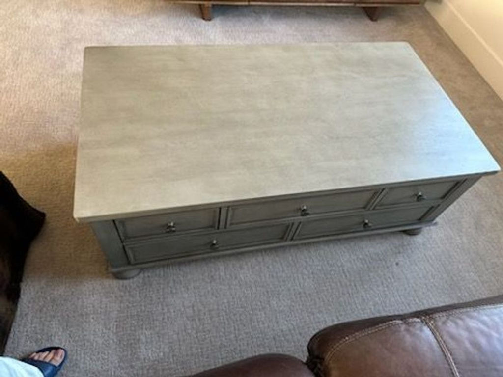 1. Rectangular Reperch coffee table with a light gray finish and multiple drawers, shown in a living room setting.