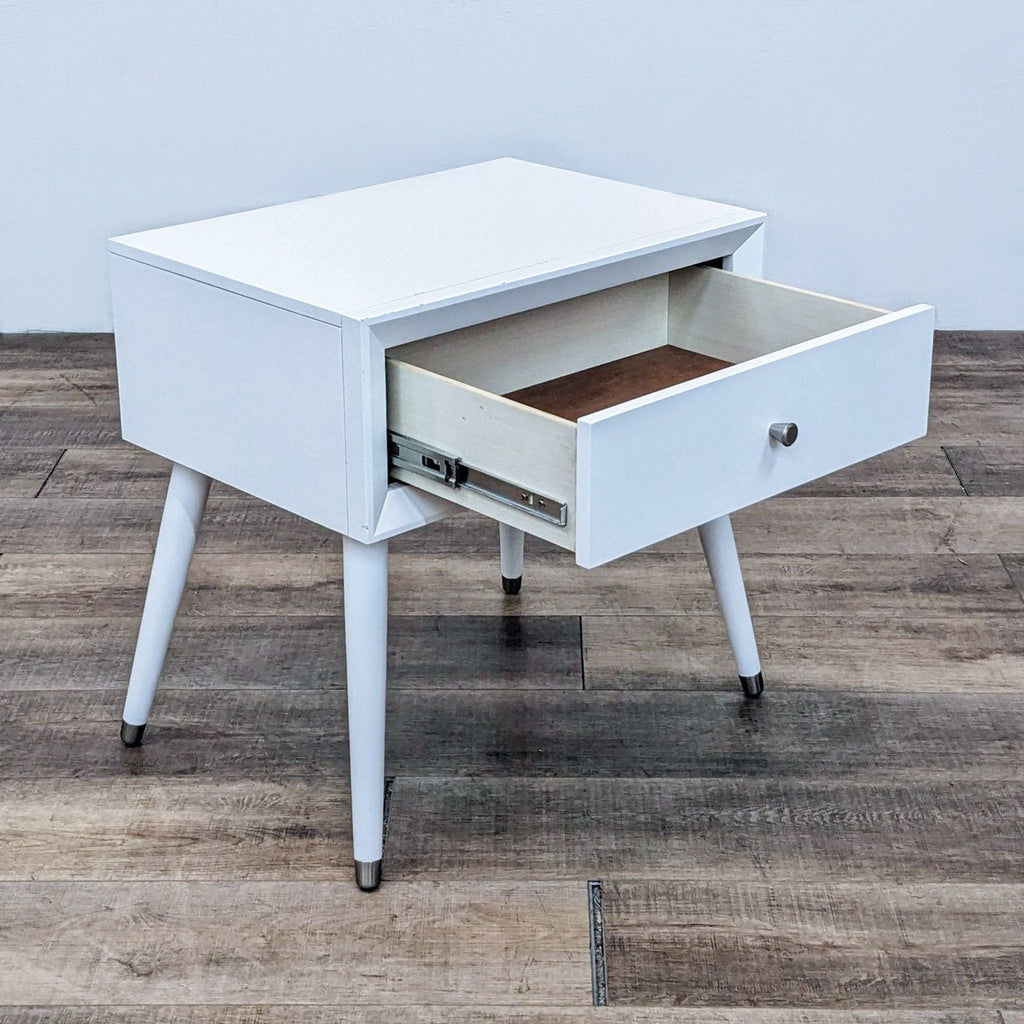 Angled view of a white end table with an open drawer revealing interior storage space.