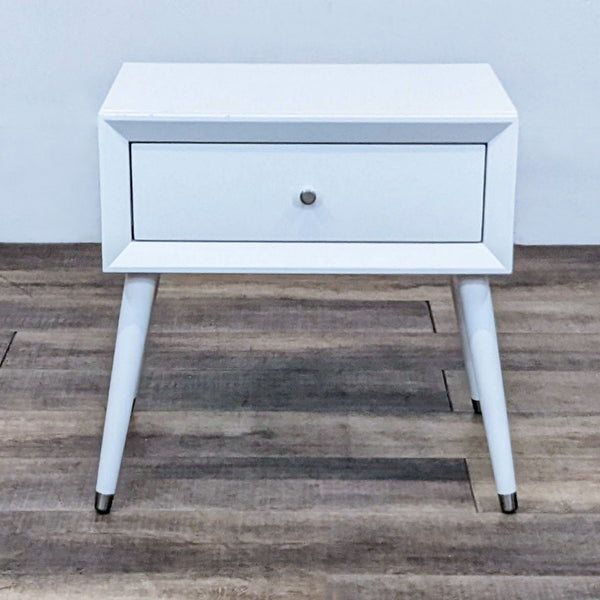 White end table with a single drawer, featuring sleek, angled legs and minimalist design.