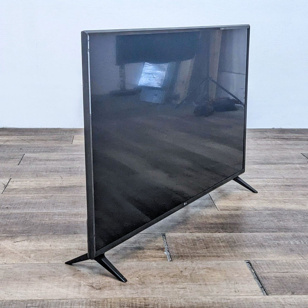 Side view of LG TV showcasing its thin profile and sleek design on wooden flooring.