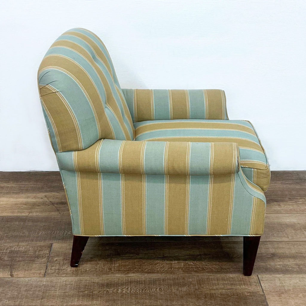 Side view of striped armchair with tufted back and rolled arms.
