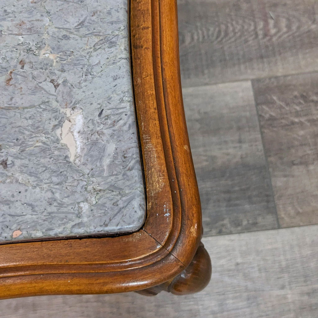 Close-up of the marble top and wooden edge detail on the table.