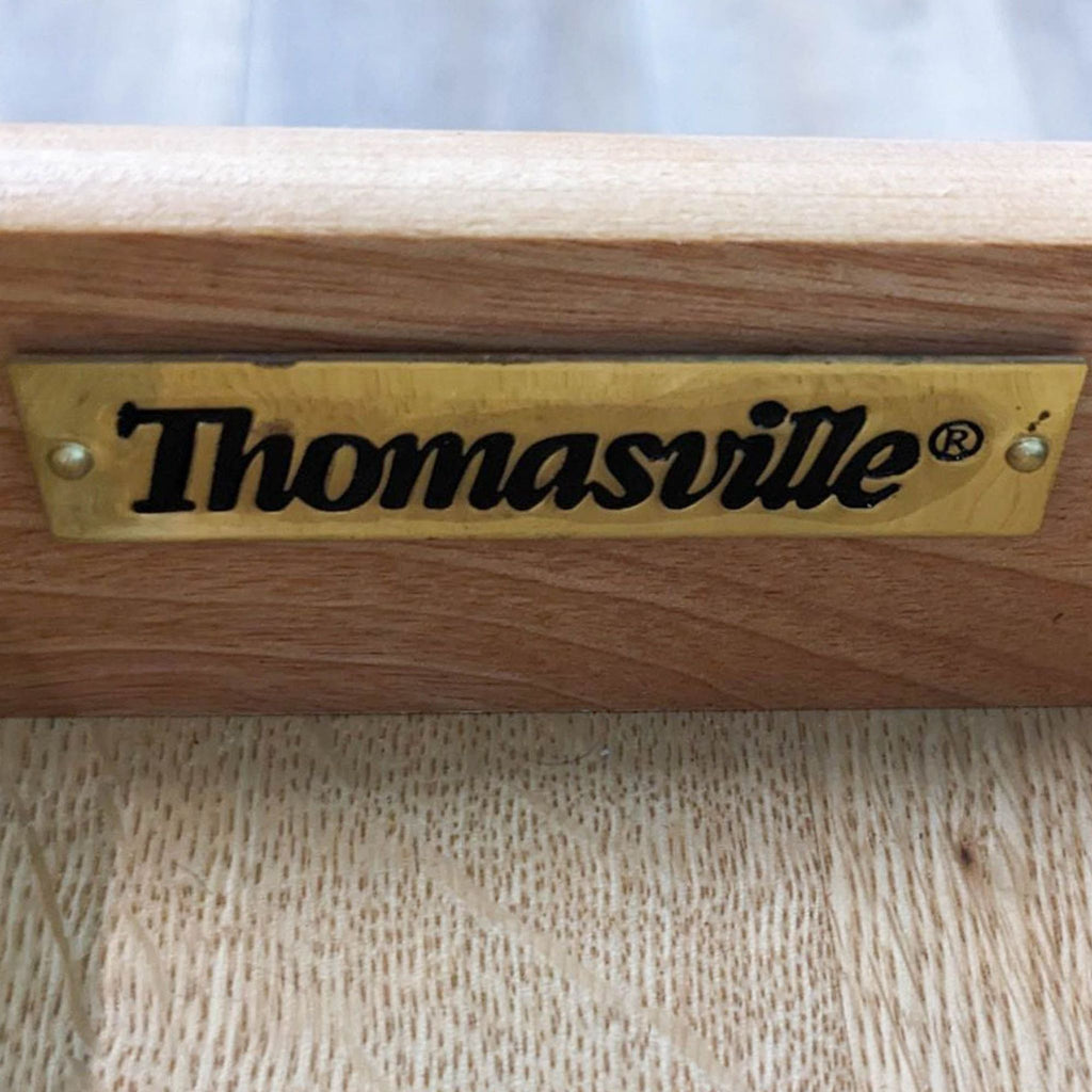 Thomasville branding on a metal label attached to a wooden surface.