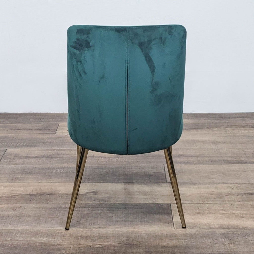 Back view of a contemporary green velvet chair with stylish gold legs.