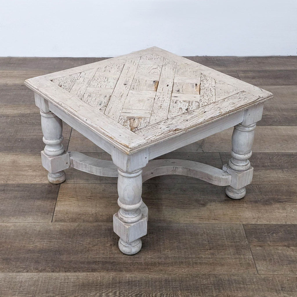 Square side table made from distressed wood with decorative legs and an antique finish.