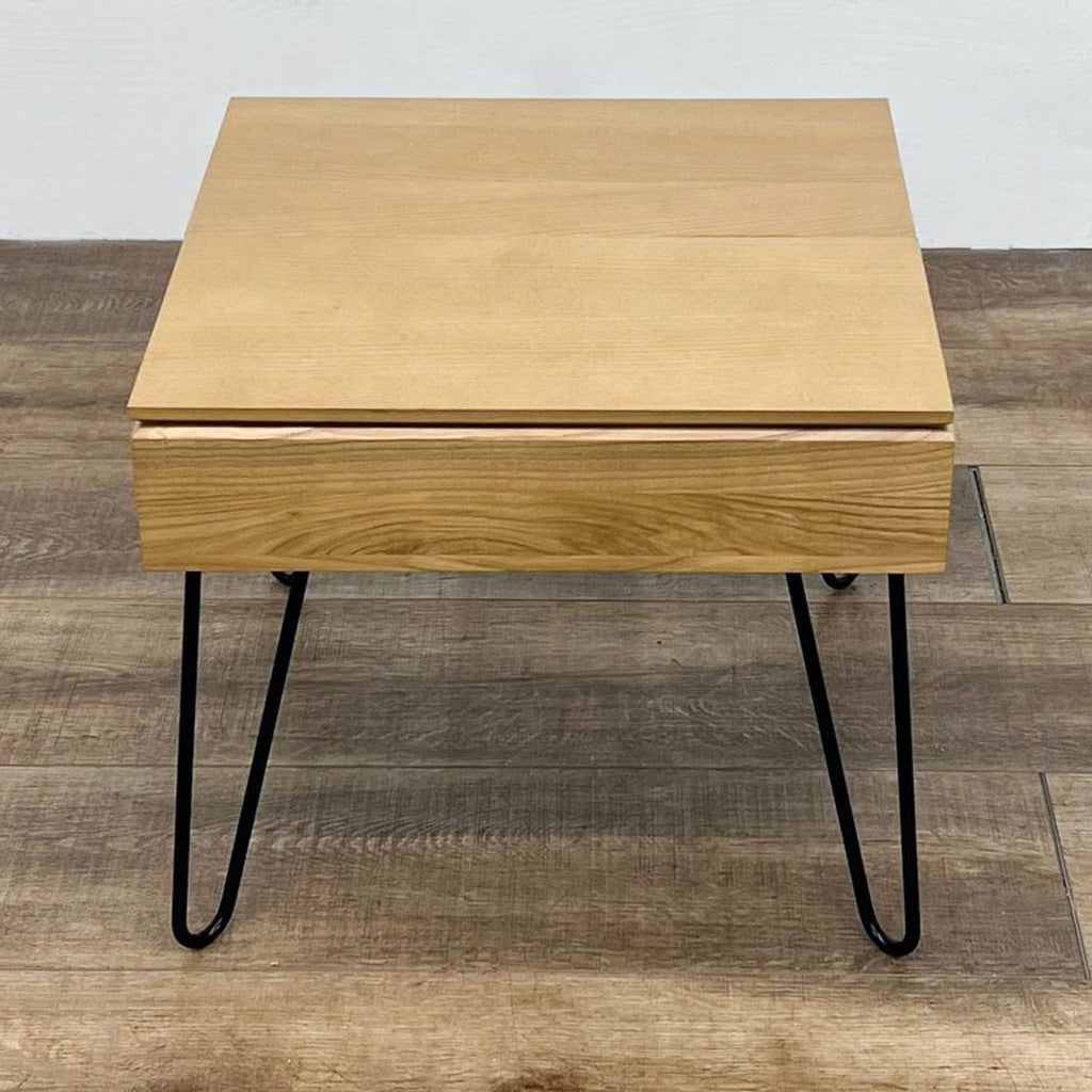 Top view of square wooden table with metal hairpin legs on a wooden floor.
