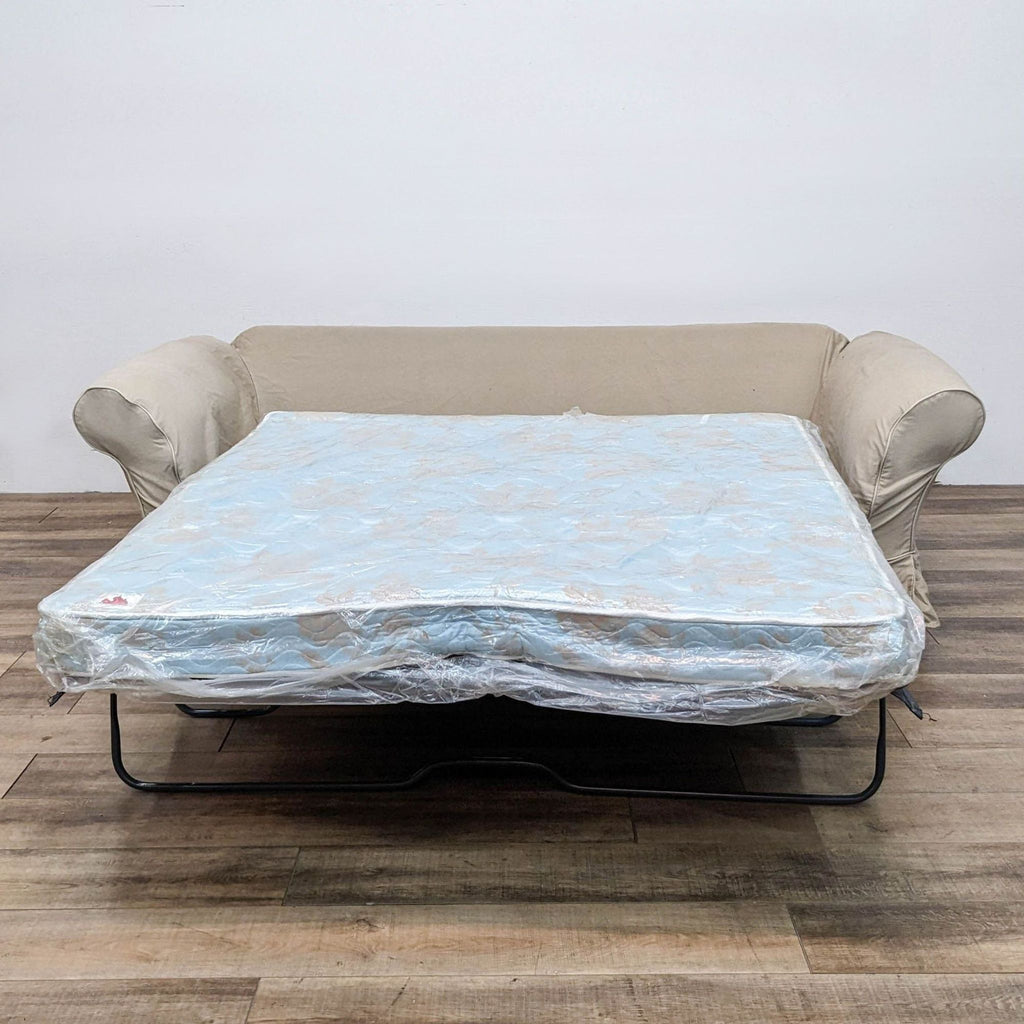 Sleeper sofa unfolded to reveal queen mattress with protective cover.