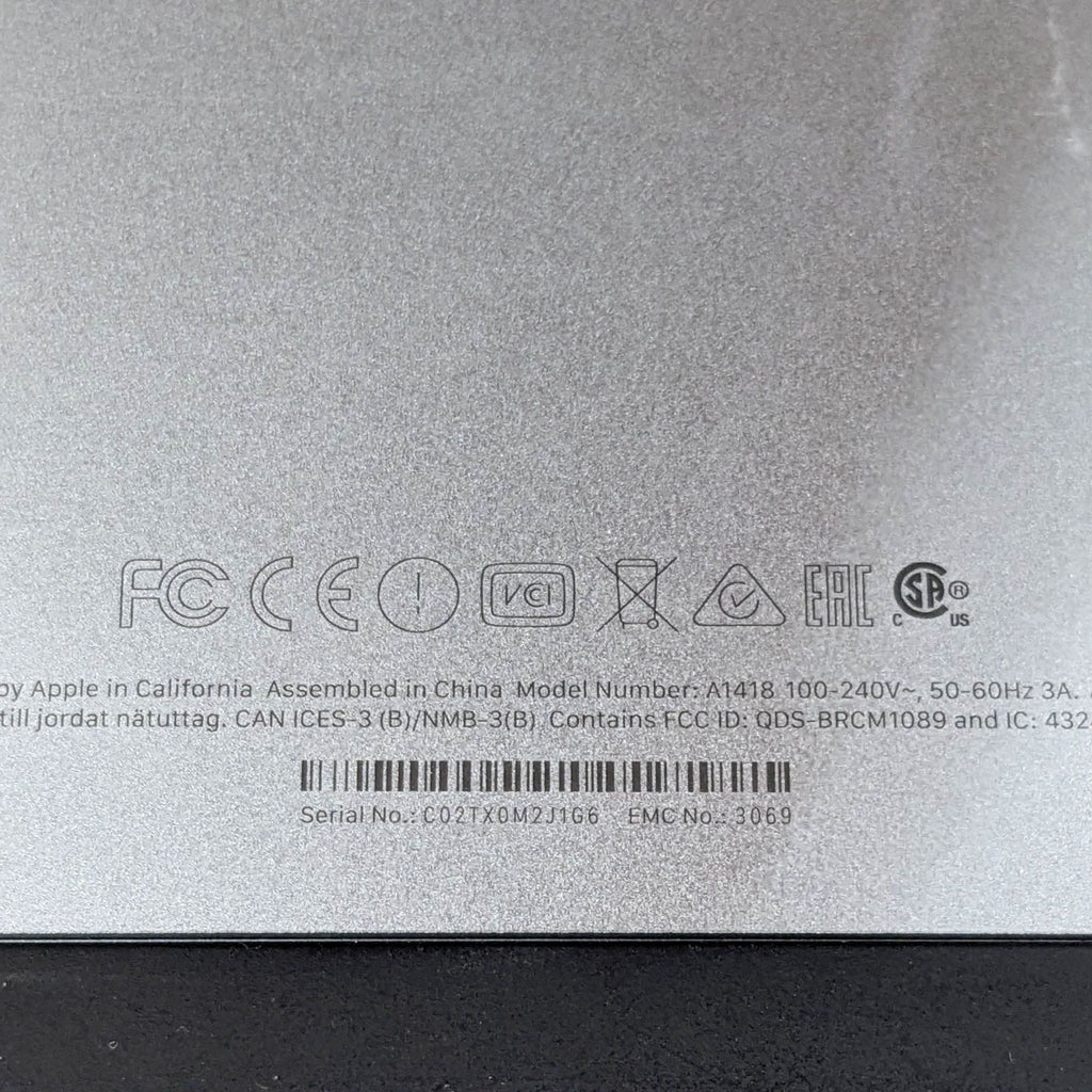 Close-up of the back of an Apple monitor showing model number A1418 and various certifications.
