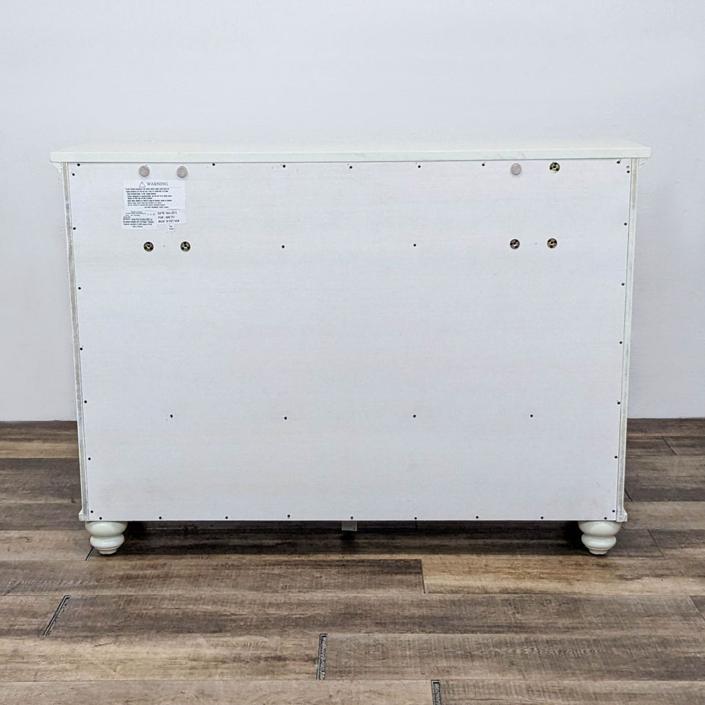 3. Backside of the Aspen Home Cambridge “Chesser” dresser, showing its flat rear panel and four rounded feet.