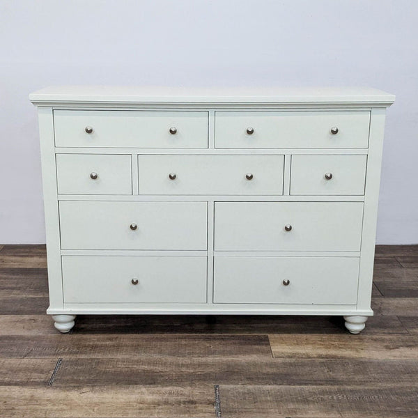 1. Front view of a white Aspen Home Cambridge “Chesser” dresser with 9 drawers and pewter hardware.  