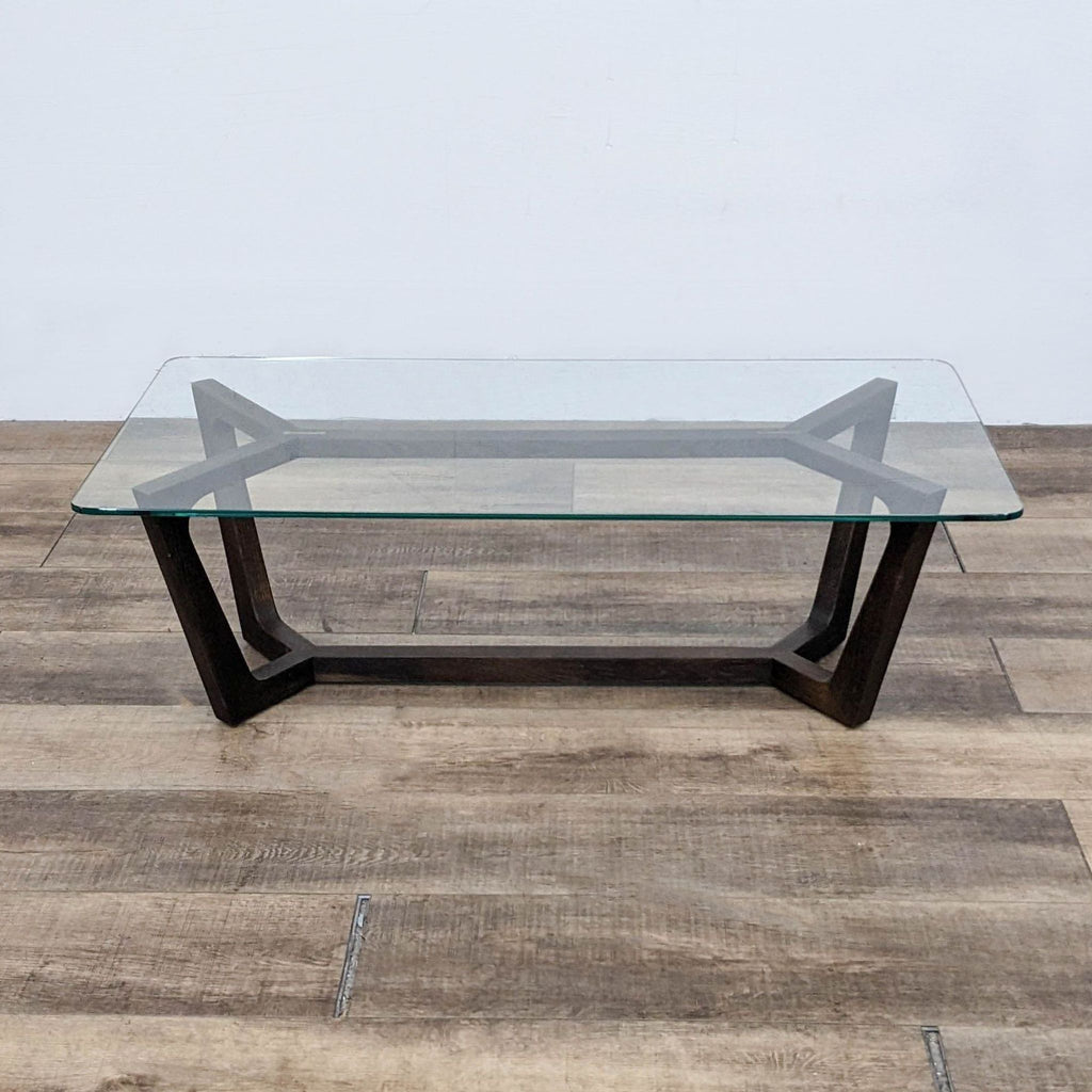 Square glass coffee table with a dark wood trestle base from Square Roots Furniture.