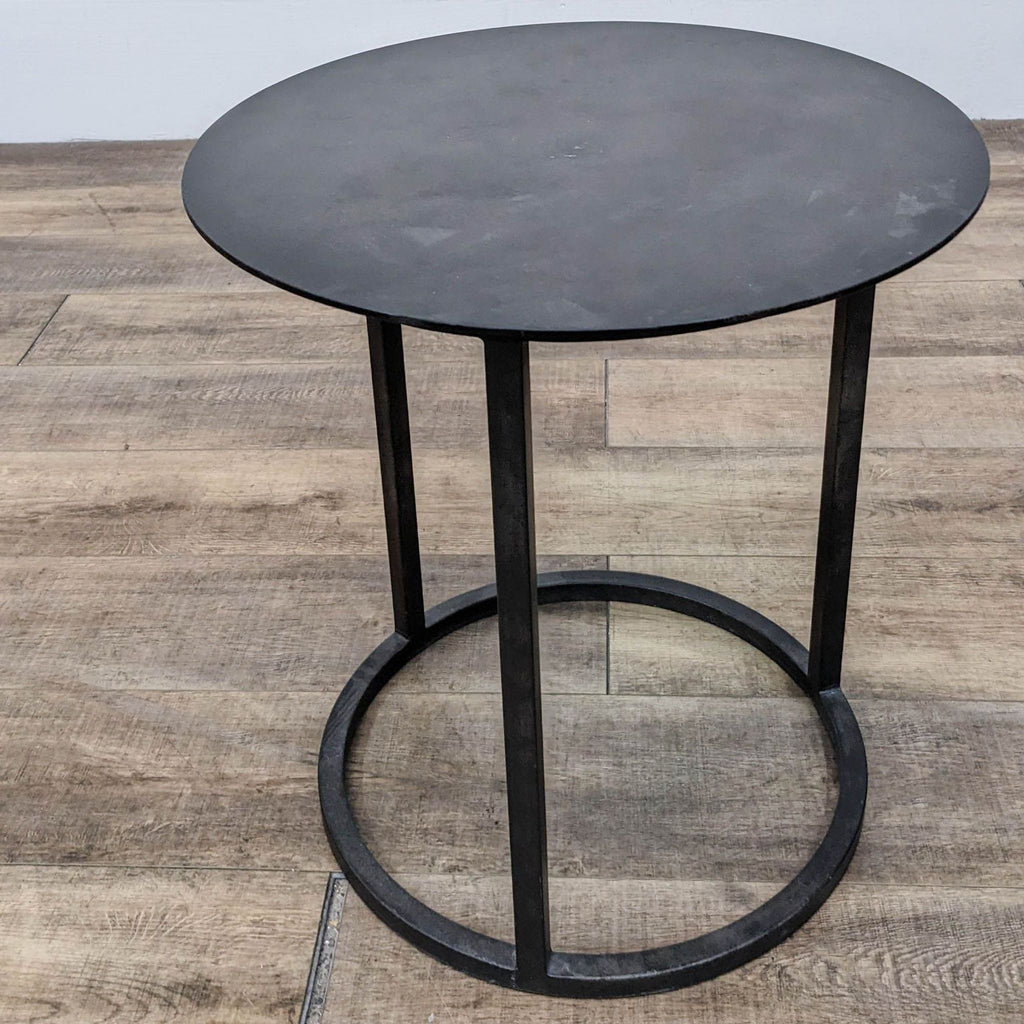 Round metal side table by Restoration Hardware on wooden floor.