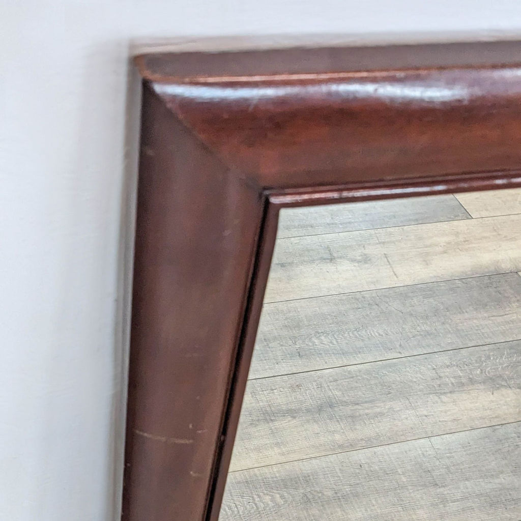Close-up of light cherry stained wooden frame of traditional-style mirror.