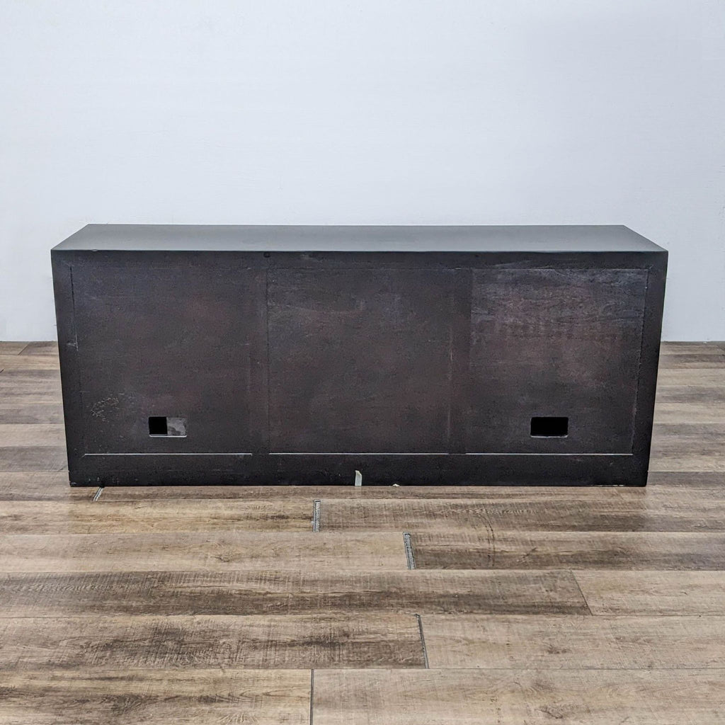 Back view of black-framed entertainment center with cable management holes.
