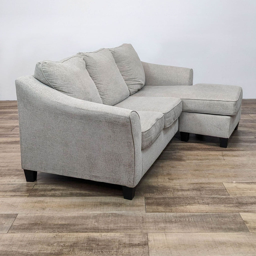 Side view of a driftwood sectional sofa with dark feet and flared arms.