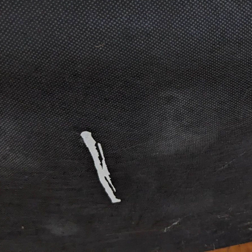Close-up of a small scratch on a dark fabric surface of a chair.
