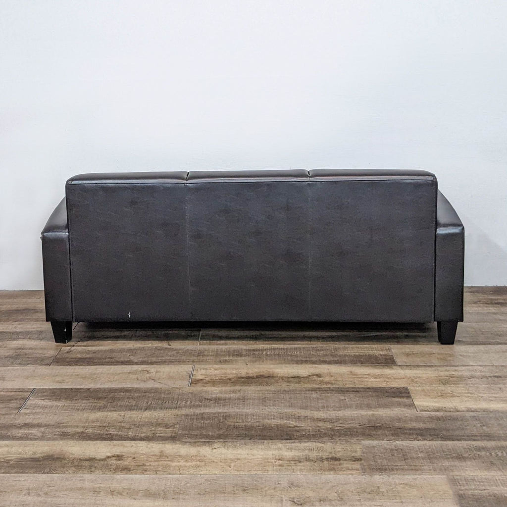 a black leather couch sitting on a floor 