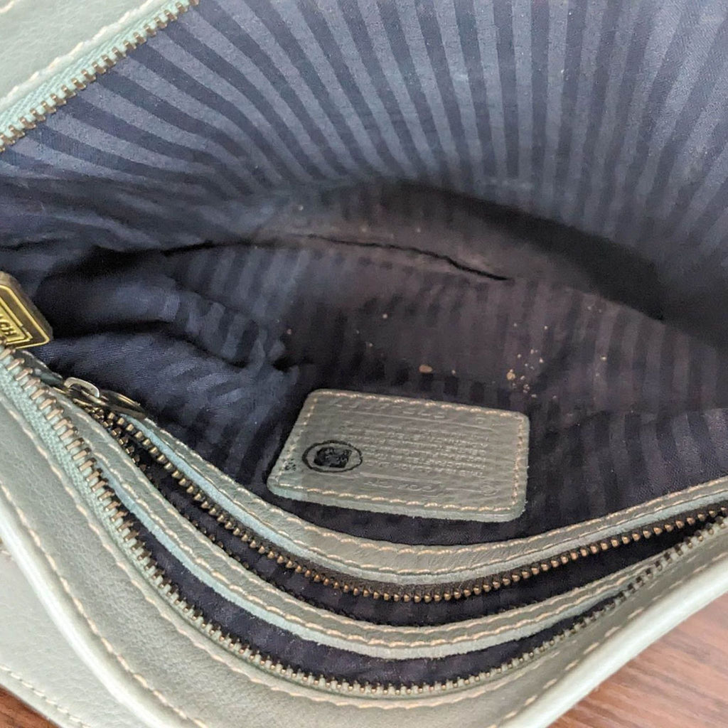 Interior of a Coach purse featuring striped fabric lining.