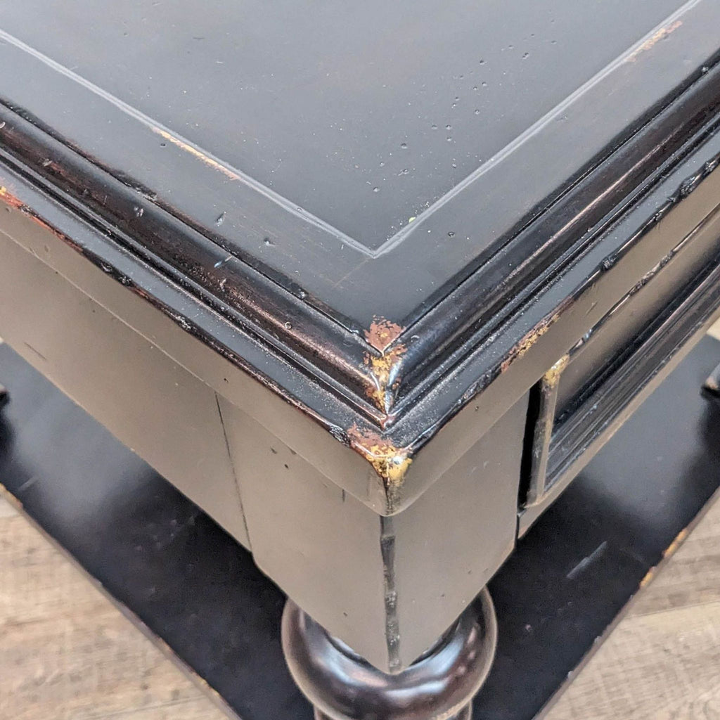 3. Close view of the distressed black finish and wood detailing on the Tommy Bahama end table corner.