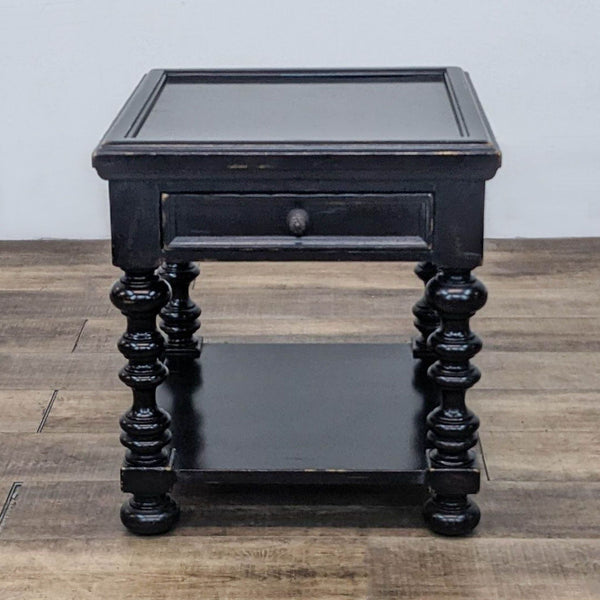 1. Black wood end table by Tommy Bahama, features turned legs, a drawer, and lower shelf, distressed finish.