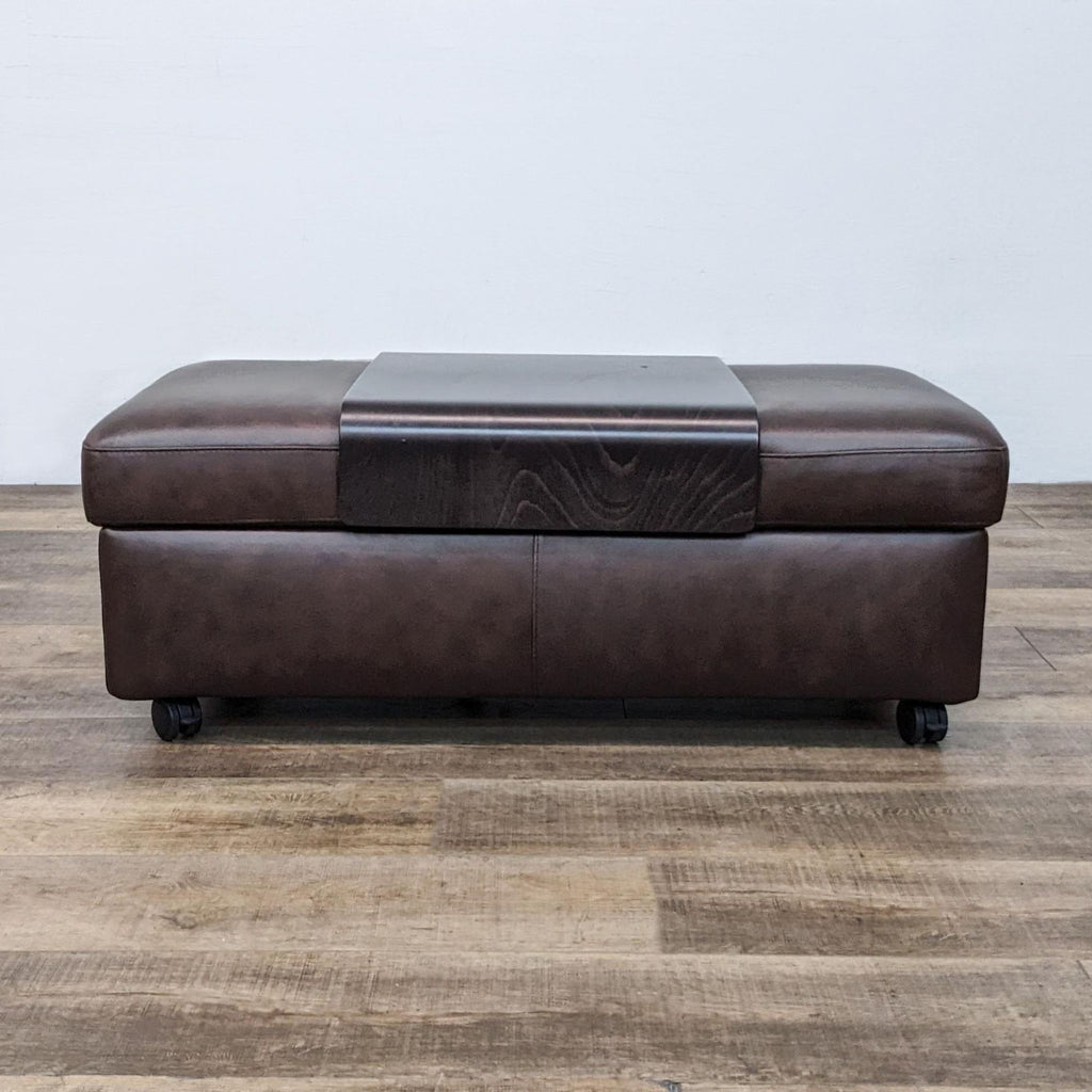 2. Front view of a brown leather ottoman with a central wooden section.