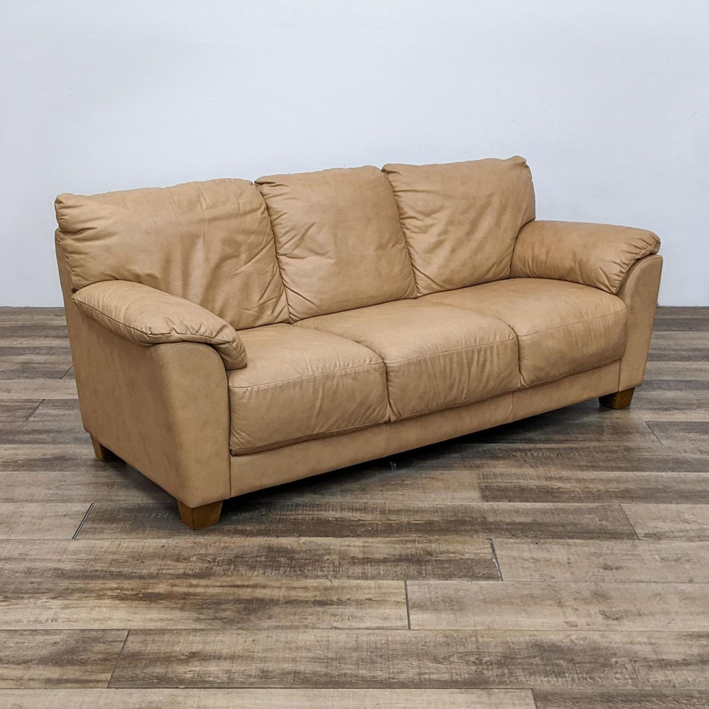 Angled view of a 3-seat tan leather sofa on wood floor.