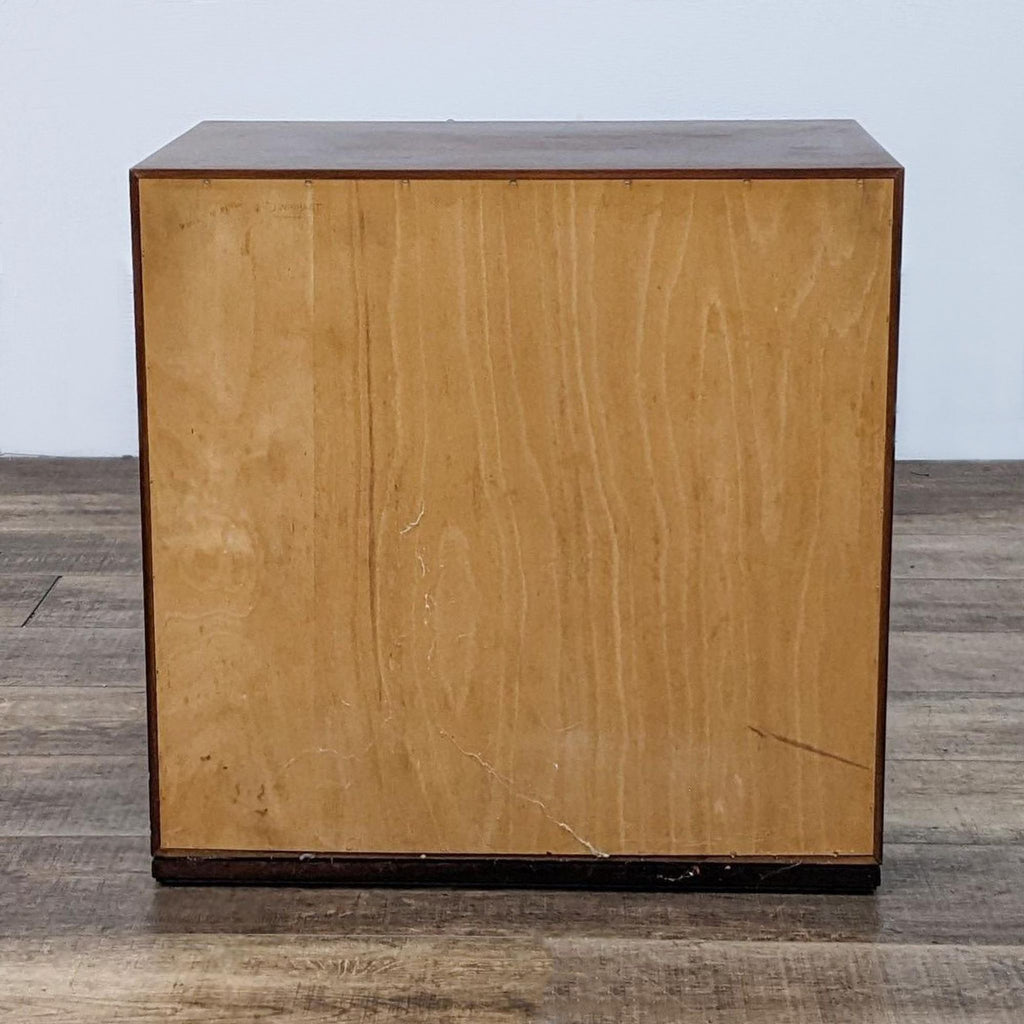 Back panel of a wooden dresser with a plain finish.