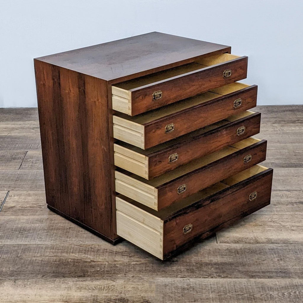 Side view of a wood dresser with open drawers and brass handles.