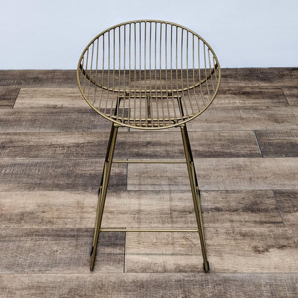 Rounded back gold stool with slat design and footrest on wooden floor.