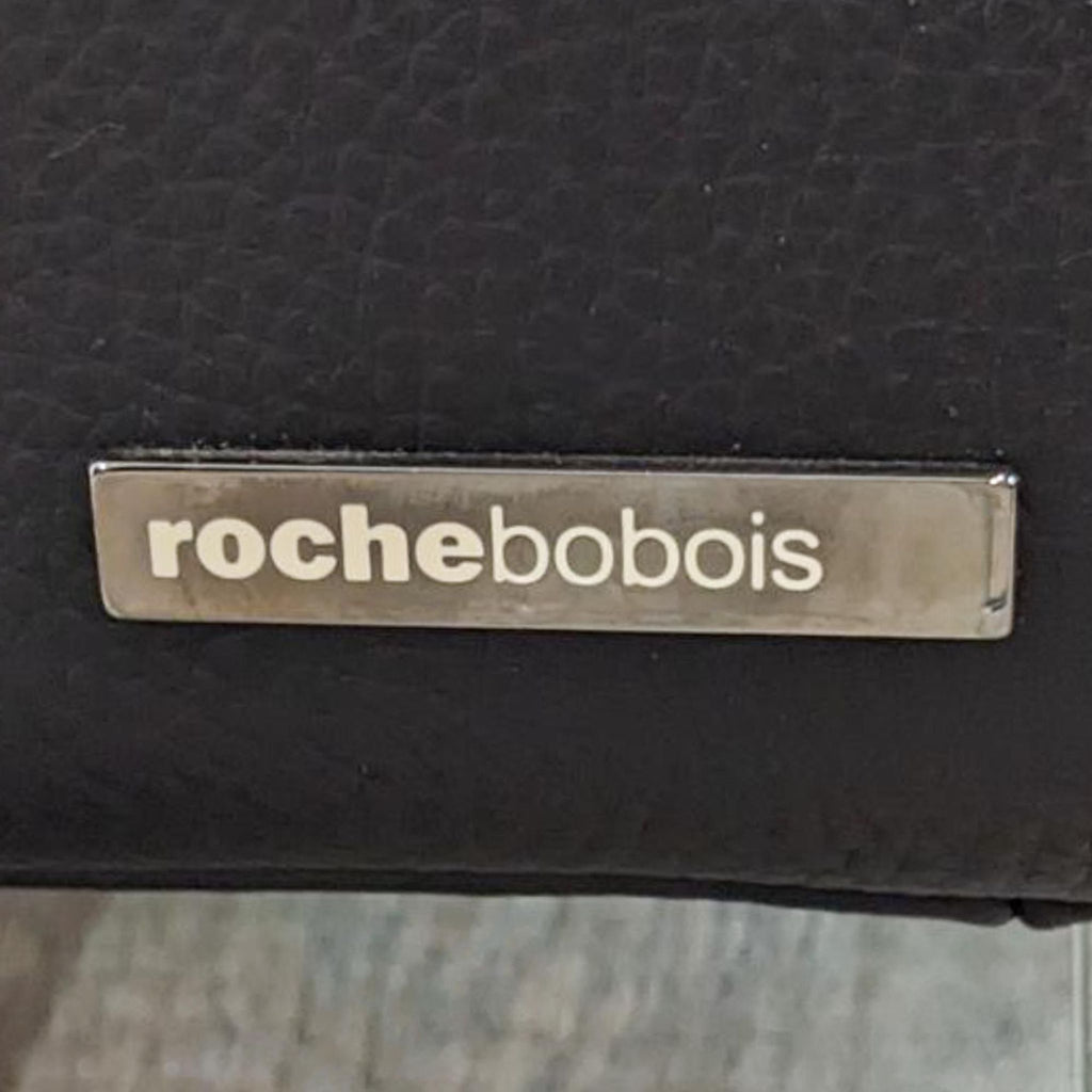 Close-up of Roche Bobois brand label on black leather.