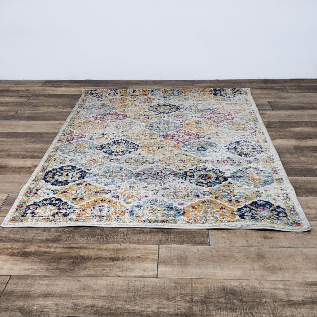 Distressed floral area rug with vibrant colors on a wooden floor.