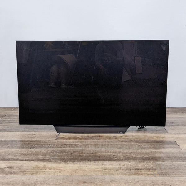 Front view of a black LG TV on a wooden floor.