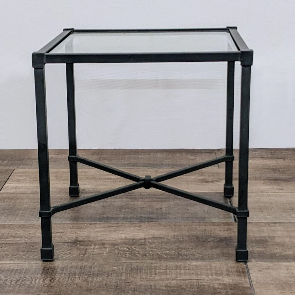 Square table with aluminum frame and glass top, featuring crossbar support.