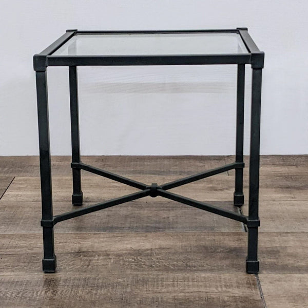 Square table with aluminum frame and glass top, featuring crossbar support.