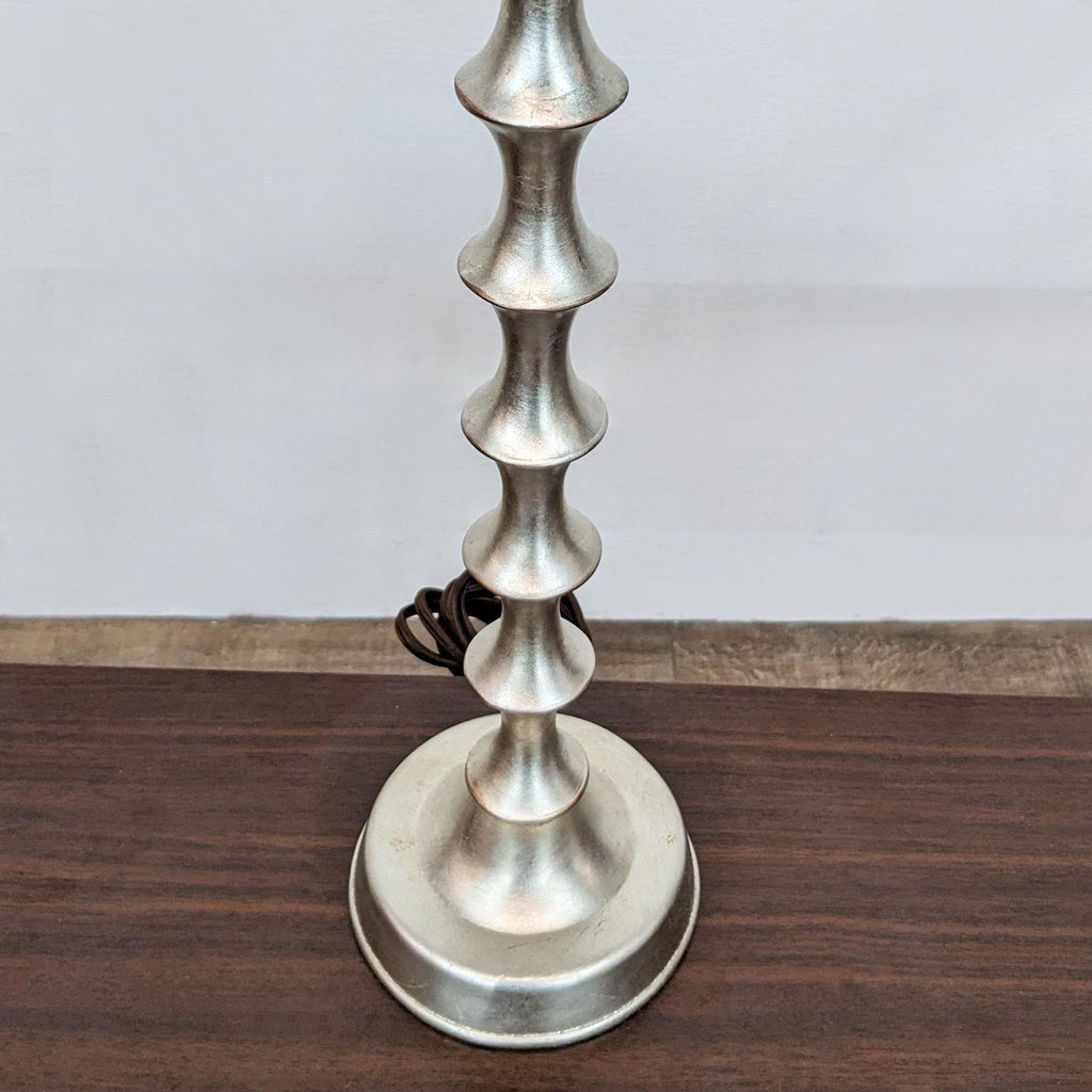 Base of the Reperch lamp showing its unique metallic design on a wooden surface.