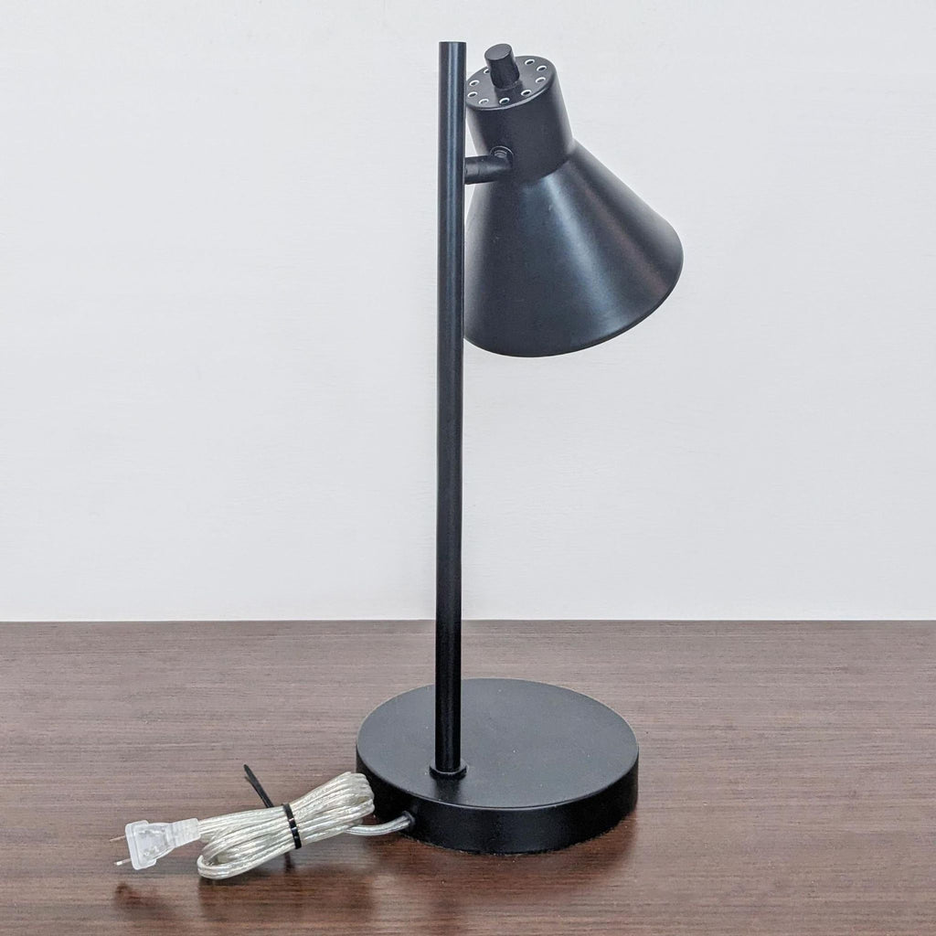 Side view of the Reperch table lamp with a cord coiled on a wooden table.