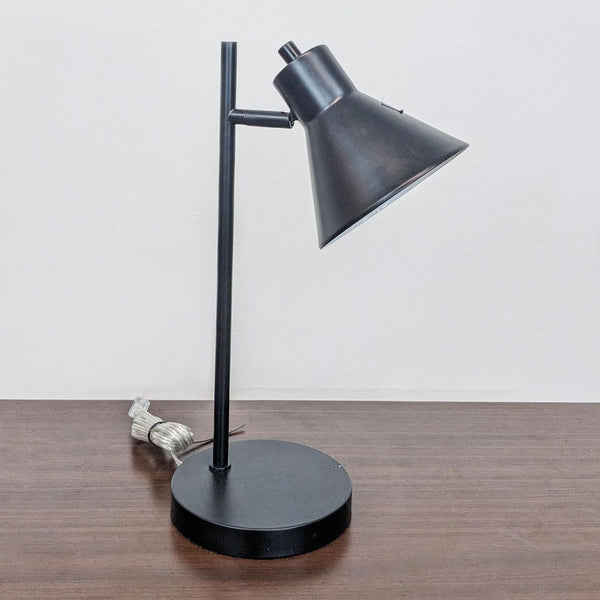 Black Reperch table lamp with angled conical shade on a wooden surface.